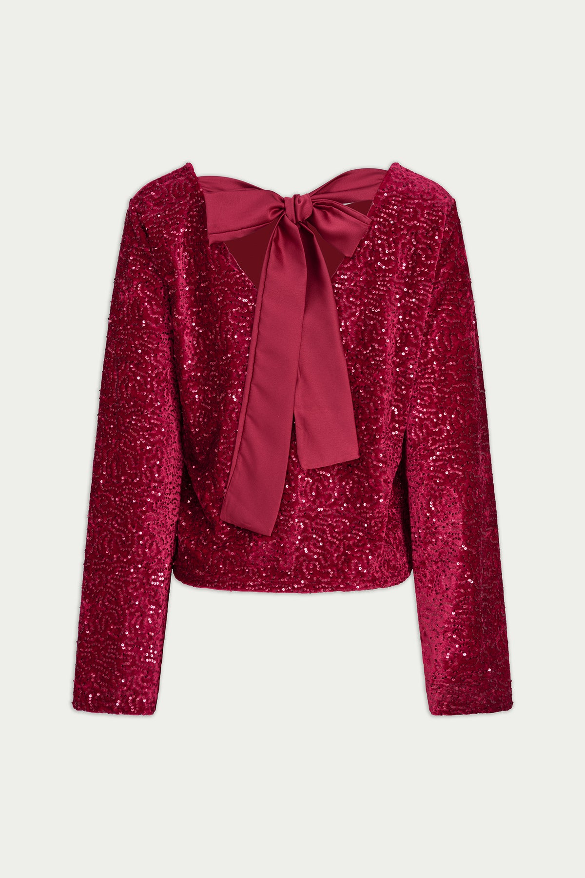 A long-sleeve cropped jacket covered in shimmering magenta sequins, featuring a large satin bow at the square neckline, shown against a light gray background.