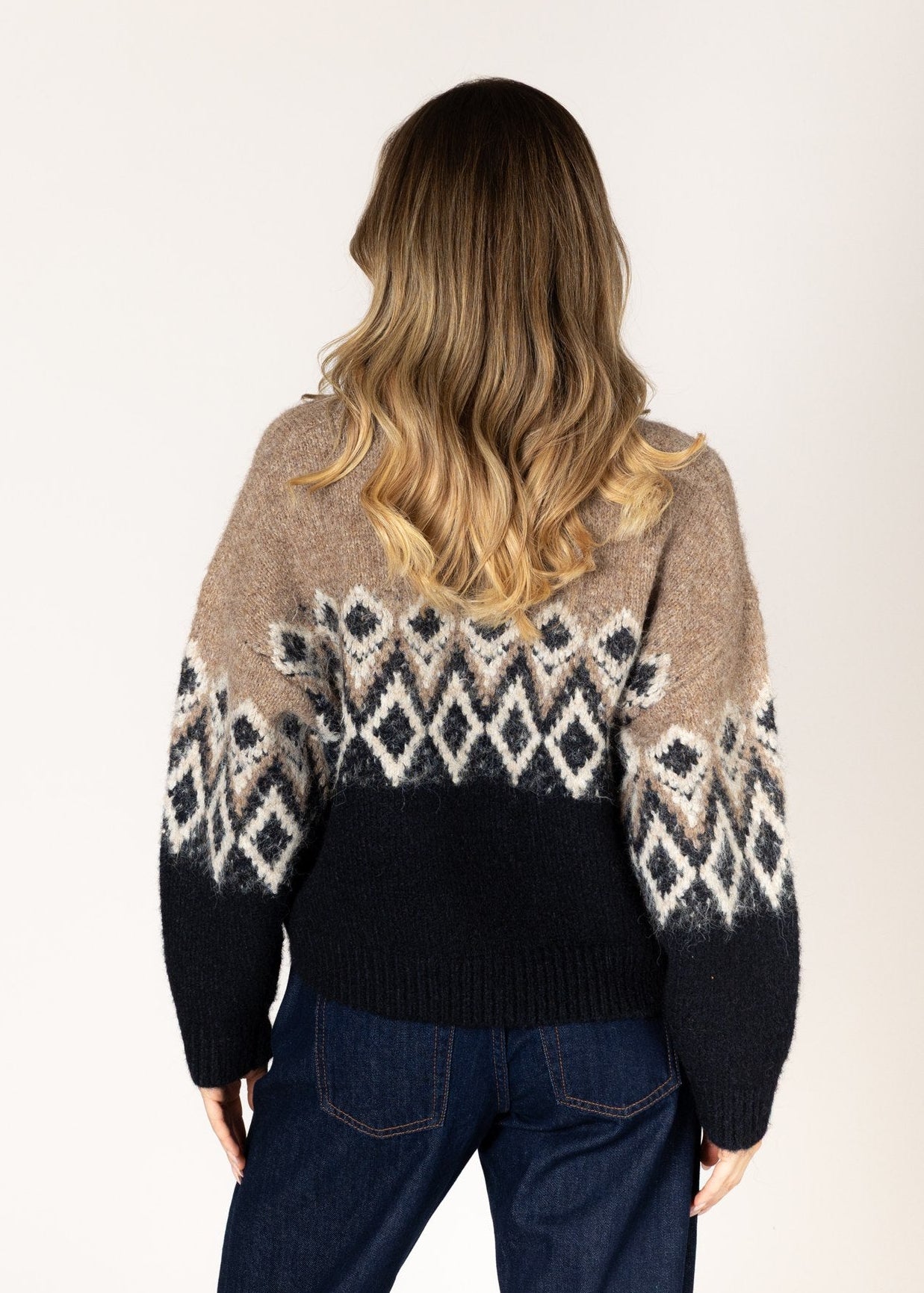 Person wearing a patterned sweater with a neutral background