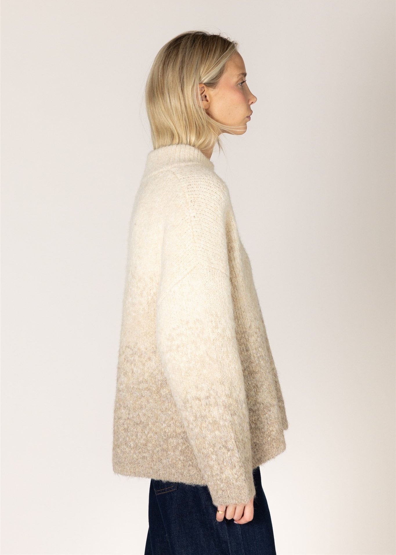Woman wearing a beige cape against a plain background