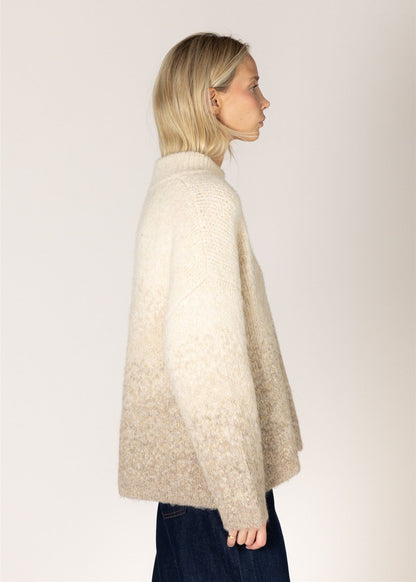 Woman wearing a beige cape against a plain background